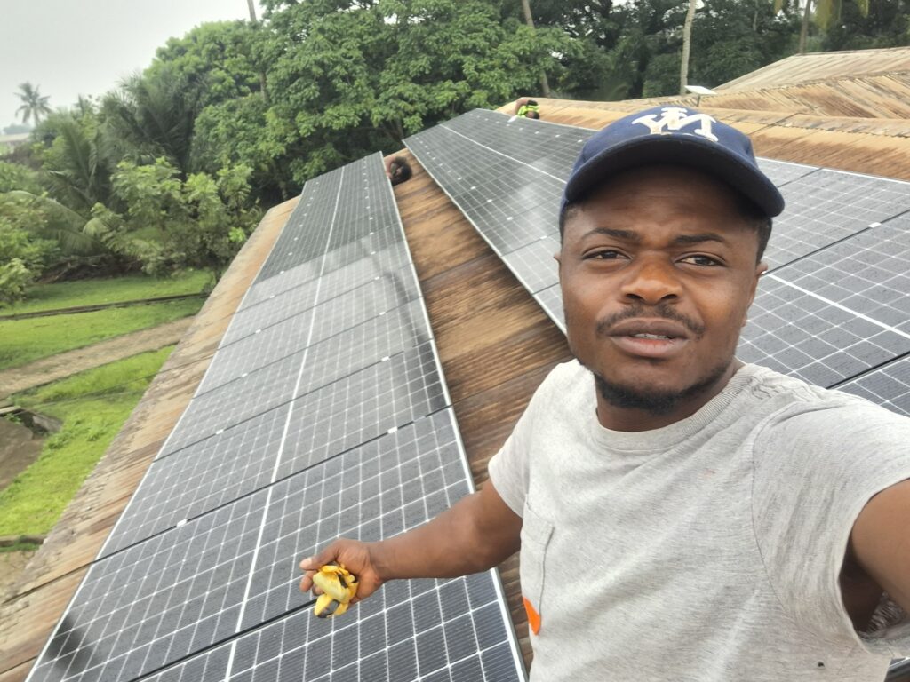 Chrysantus on a roof with solar panels in Kumba.