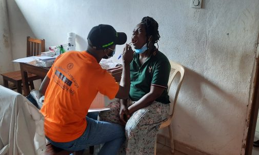 A doctor putting a small mirror in a girls mouth to check her teeth.
