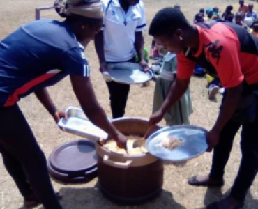 Teachers are getting food for students from a pot.