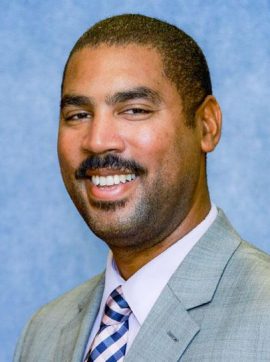 Dr. Malcolm K. Oliver smiling with a suit on.